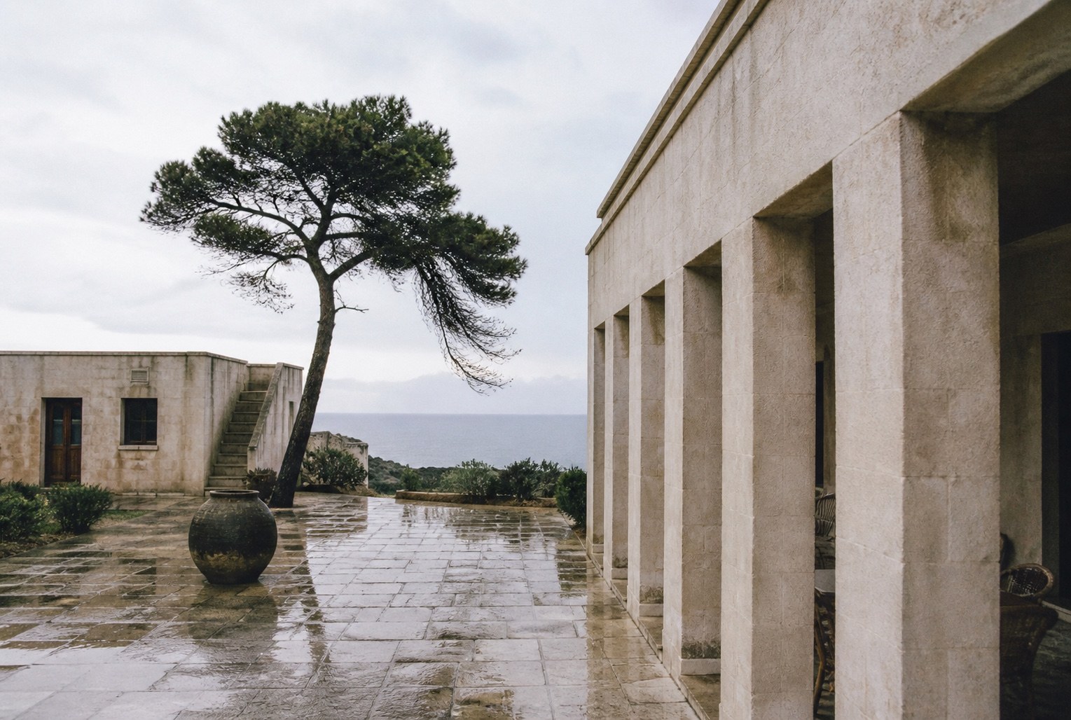 Rain-darkened stone courtyard beside a muted sea.