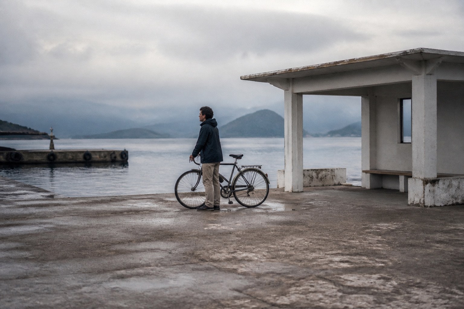 Traveler with a bicycle waiting at a quiet ferry landing.
